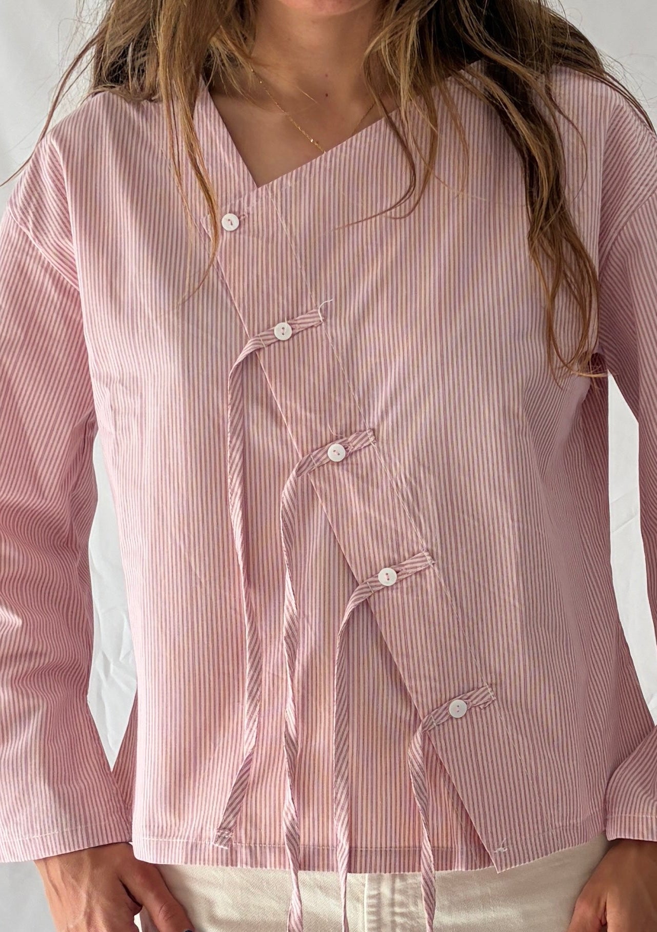 Detalle parte frontal blusa asimétrica con detalle de flecos. Color rosa